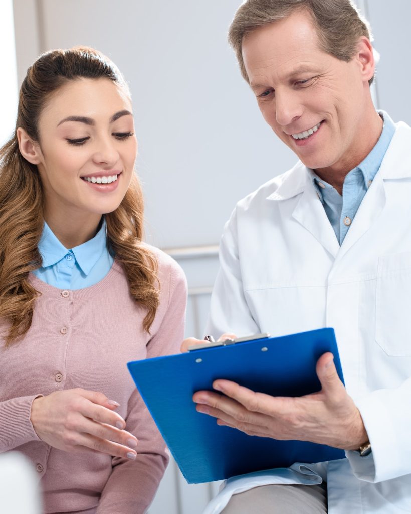 handsome-doctor-showing-something-in-clipboard-to-smiling-patient-in-clinic.jpg